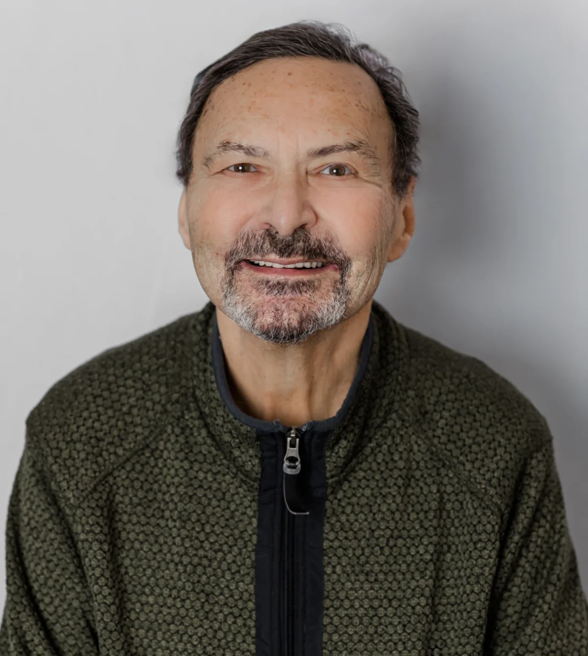 Salt and pepper bearded man portrait in dark knit sweater on light background