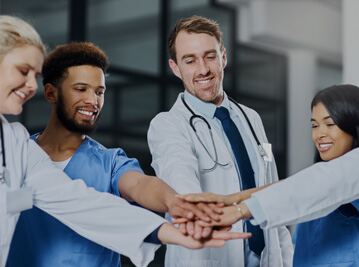 Healthcare team collaboration with smiling doctors linked hands in modern medical office